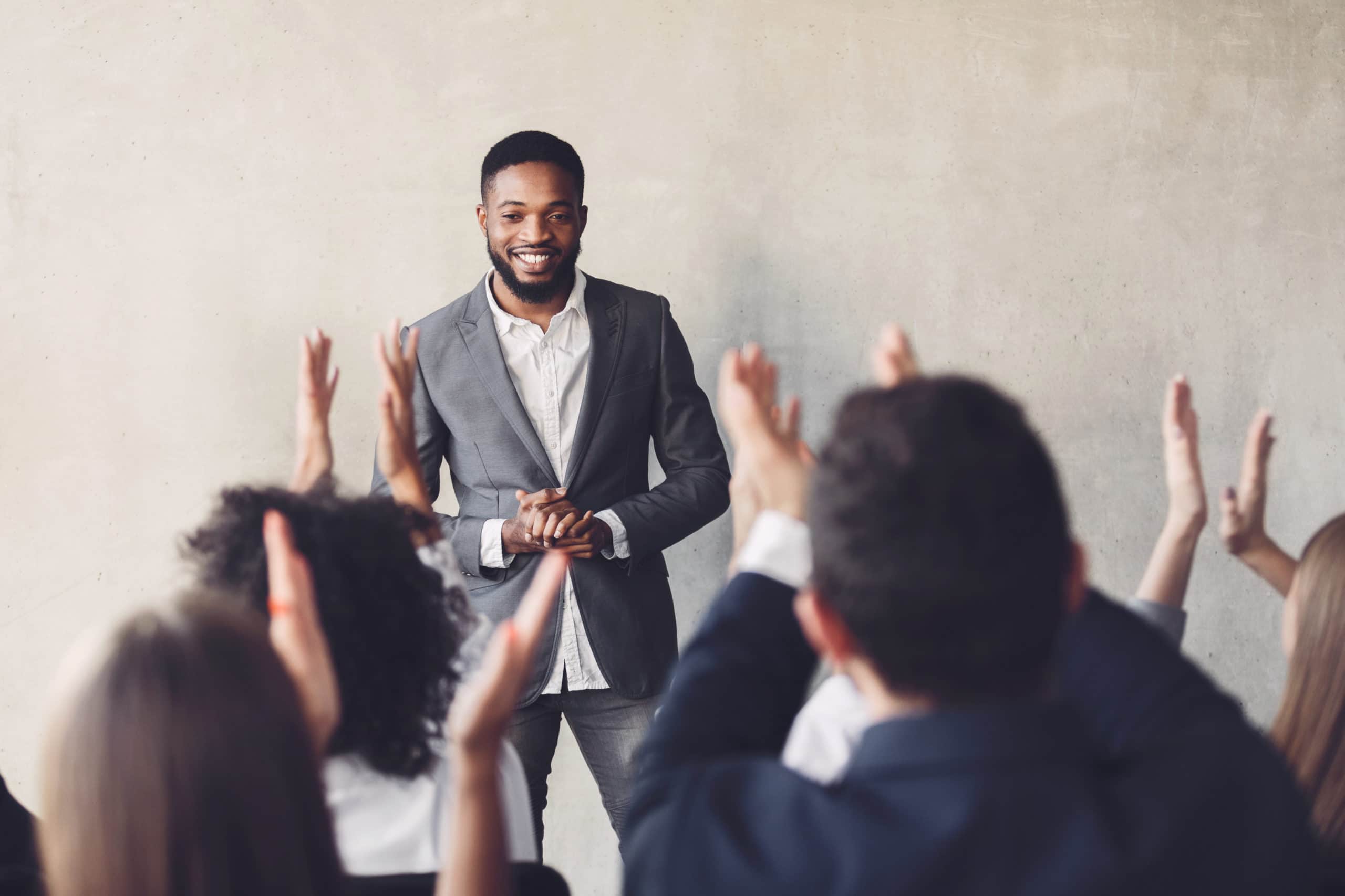 Audience clapping hands to speaker after business seminar